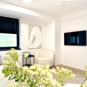 Część wypoczynkowa z fotelem i telewizorem w apartamencie 12