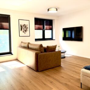 Salon z telewizorem i wejściem do sypialni w apartamencie 26